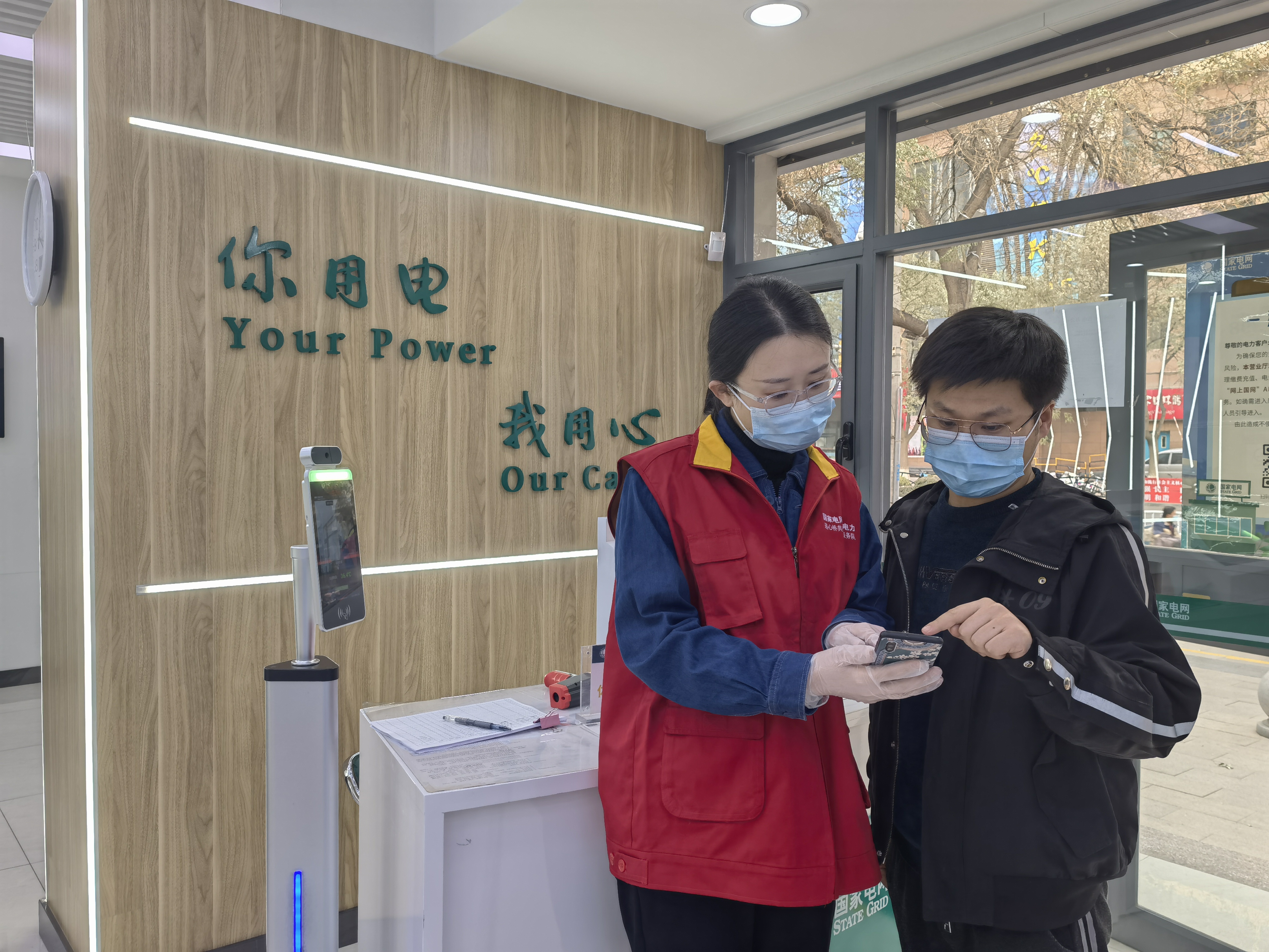 國網蘭州供電公司青年員工在費家營營業廳向客戶推廣“網上國網”APP線上辦電功能。何英攝.jpg